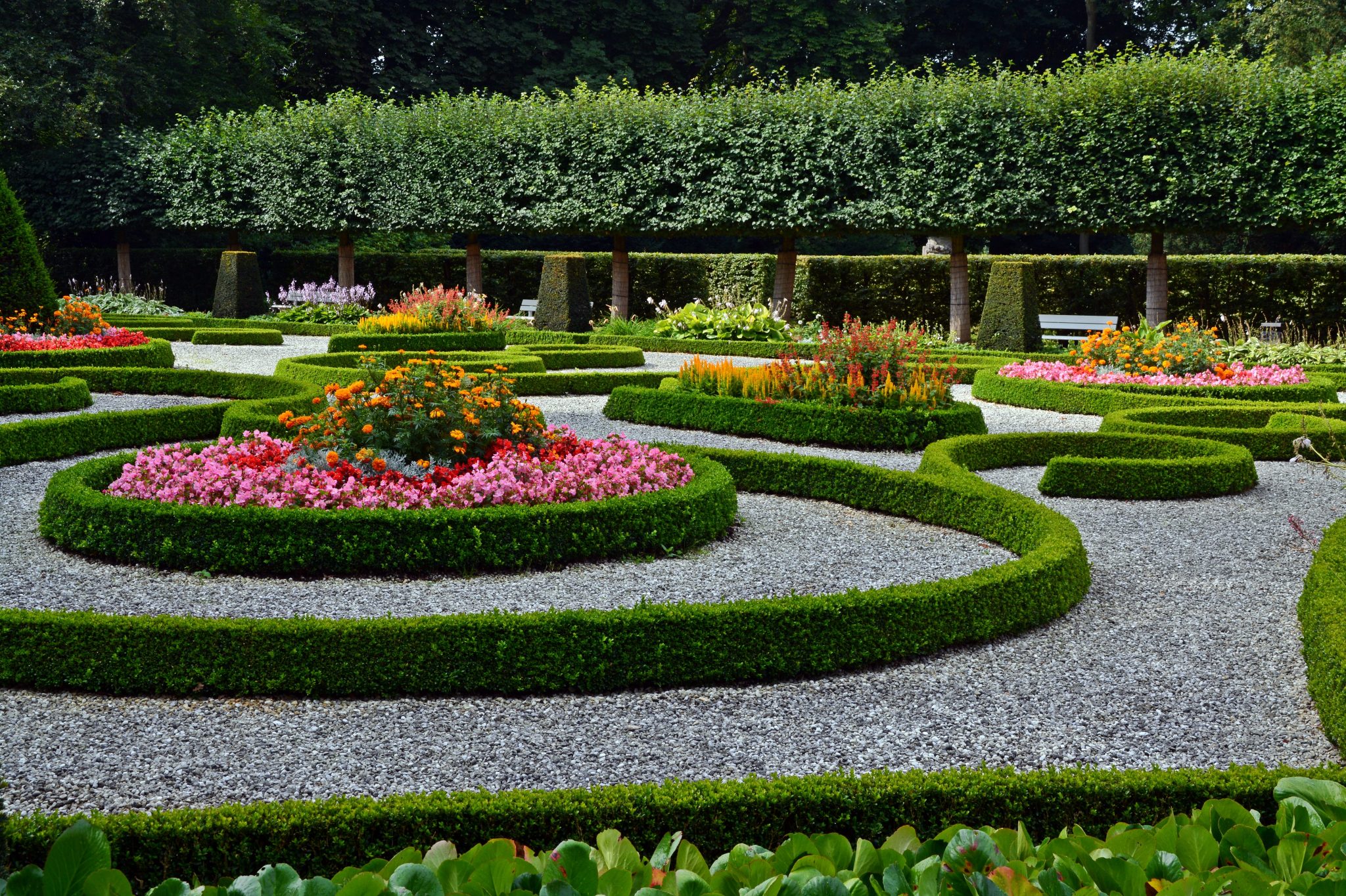 Formal angelegter Ziergarten mit geschnittenen Buchsbaumhecken und farbigen Blumenbeeten