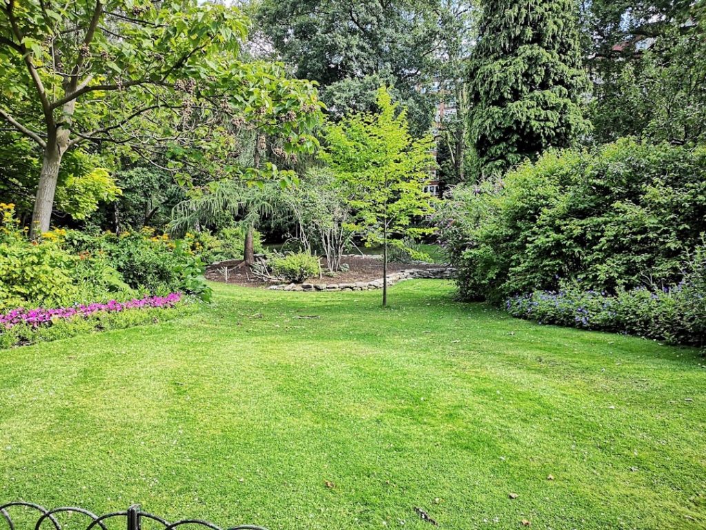 Gepflegter Rasen mit Blumenbeeten und Gehölzen